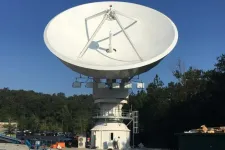 Thumbnail for Large white satellite dish antenna mounted outdoors with trees and clear sky in background