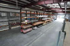 Thumbnail for Warehouse interior with metal racks holding wood planks and building materials in an organized industrial space.