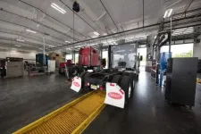 Thumbnail for Inside a large truck repair shop with semi-trucks and maintenance equipment under bright lights.