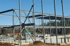 Thumbnail for Steel framework of a building under construction on a clear sunny day with construction equipment and dirt piles.