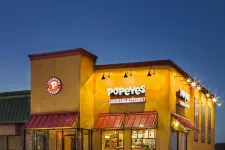 Thumbnail for Popeyes Louisiana Kitchen restaurant building illuminated at dusk with logo and red awnings.