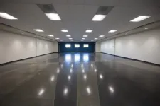 Thumbnail for Spacious empty room with polished concrete floor, white walls, ceiling lights, and three windows at the far end.