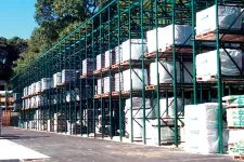 Thumbnail for Outdoor warehouse racks filled with stacked pallets wrapped in protective covers under clear sky.