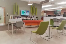 Thumbnail for Modern library teen area with green chairs, orange couch, tables, bookshelves, and digital information screen.