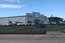 Thumbnail for Industrial warehouse building with Alexander Leasing signage, vehicles, and a freshly landscaped lawn under a clear blue sky.