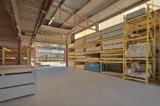 Thumbnail for Warehouse interior with construction materials stored on yellow metal shelves and pallets on concrete floor.