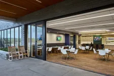 Thumbnail for Modern indoor dining area with white chairs and wood flooring opens to an outdoor patio with rocking chairs.