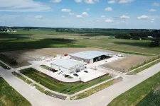 Thumbnail for Aerial view of industrial warehouse buildings surrounded by farmland and roads under a blue sky with scattered clouds
