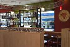 Thumbnail for Interior of a cafe with glass jars on shelves, colorful mosaic tiles, red chairs, and wooden partitions