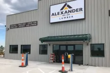 Thumbnail for Front view of Alexander Lumber building with signage, traffic cones, and large windows on a cloudy day