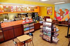 Thumbnail for Interior view of a Dunkin' Donuts with menu boards, coffee display, and seating area including mural artwork.