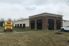 Thumbnail for Mini Storage Depot building with black awnings and yellow-red sign on lawn under cloudy sky