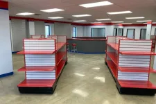 Thumbnail for Empty red and white retail display shelves in a spacious, well-lit store interior with polished concrete floors