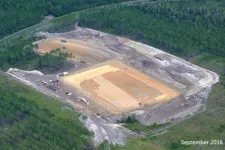 Thumbnail for Aerial view of a large construction site cleared in a forested area with earthmoving equipment and vehicles