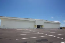 Thumbnail for Empty parking lot in front of a large white commercial building under a clear blue sky.