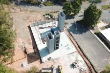 Thumbnail for Aerial view of early-stage concrete building construction with tall vertical structures and surrounding cleared land.