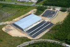 Thumbnail for Aerial view of a large industrial warehouse under construction surrounded by greenery and roads.