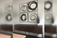 Thumbnail for Modern interior with wooden sideboard, black marble top, potted plant, and four abstract black and white circle paintings.