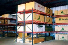 Thumbnail for Warehouse interior showing stacks of lumber on metal racks under a corrugated roof with branded packaging