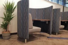 Thumbnail for Modern workspace booths with cushioned seats and privacy panels alongside a potted plant in office environment.