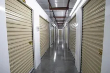 Thumbnail for Indoor hallway of a storage facility with closed beige roll-up doors on both sides and polished concrete floor