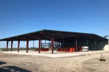 Thumbnail for Steel-framed open warehouse under construction with a green roof on a clear sunny day in a rural area.