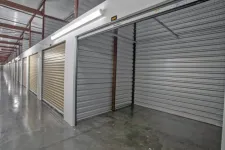 Thumbnail for Interior view of a self-storage facility with open and closed metal roll-up doors and polished concrete floors.