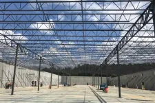 Thumbnail for Steel framework and concrete walls of a large industrial building under construction with clear blue sky.