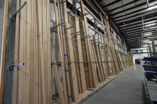 Thumbnail for Rows of wooden planks neatly organized on metal racks inside a spacious warehouse with concrete floors.
