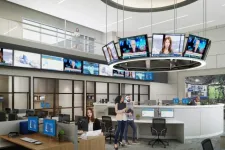Thumbnail for Modern newsroom with multiple monitors, a circular screen display, and staff working at desks and standing.
