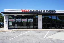 Thumbnail for Exterior of Wolf Camera & Photo store with signage announcing opening coming soon on a sunny day.