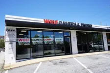 Thumbnail for Wolf Camera & Photo storefront with large windows and signs announcing opening coming soon in a small plaza.