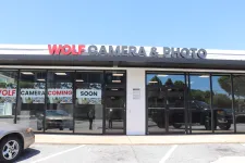 Thumbnail for Storefront of Wolf Camera & Photo with signs announcing the camera store is coming soon under clear blue sky.