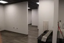 Thumbnail for Empty office space with gray walls, wood-look flooring, and various building materials and tools inside.
