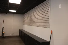 Thumbnail for Empty room with black ceiling, wood flooring, dark cabinets, and cleaning tools against white walls.