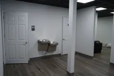 Thumbnail for Interior of a modern indoor space with two white doors, dual water fountains, and wood-look flooring.