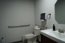Thumbnail for Accessible public restroom with toilet, sink, handrails, paper towel dispenser, and mirror in a clean, simple layout.