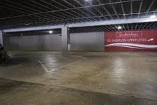 Thumbnail for Empty indoor parking garage with concrete floor and a sign directing to shops on the upper level