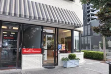 Thumbnail for State Farm office entrance with striped awning, health and business sign, next to Rosy Alterations shop window.