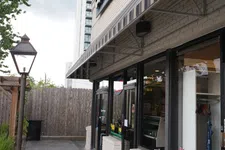 Thumbnail for Outdoor view of a beige brick commercial building with striped awning and Murphy Beds sign on window.