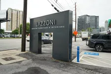 Thumbnail for Lazzoni modern furniture and interiors black entrance sign on city street with nearby cars and buildings