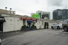 Thumbnail for Exterior of White House Restaurant with parking lot and modern city buildings on a cloudy day