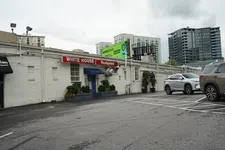 Thumbnail for Exterior of White House Restaurant with parking lot and city buildings under cloudy sky