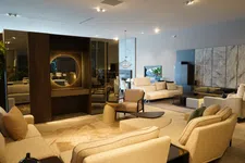 Thumbnail for Spacious modern living room with beige sofas, armchairs, circular mirror, and warm ambient lighting.