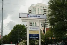 Thumbnail for Outdoor multi-business sign for PGA Tour Superstore, Men's Wearhouse, Icebox, Verizon with city buildings and trees.