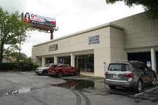 Thumbnail for Exterior of a building with cars parked outside and signage displaying lessons, repairs, and fittings.