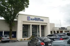Thumbnail for Front view of PGA Tour Superstore with parked cars and adjacent Men’s Wearhouse store in daylight
