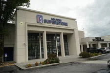 Thumbnail for Exterior view of PGA Tour Superstore with large glass doors and adjacent Men's Wearhouse store in a shopping center