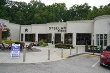 Thumbnail for Exterior view of Stellar Bodies storefront with outdoor seating and Mai Thai restaurant open sign in front.