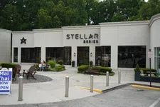 Thumbnail for Exterior view of Stellar Bodies fitness studio with outdoor benches, greenery, and parking area in front.